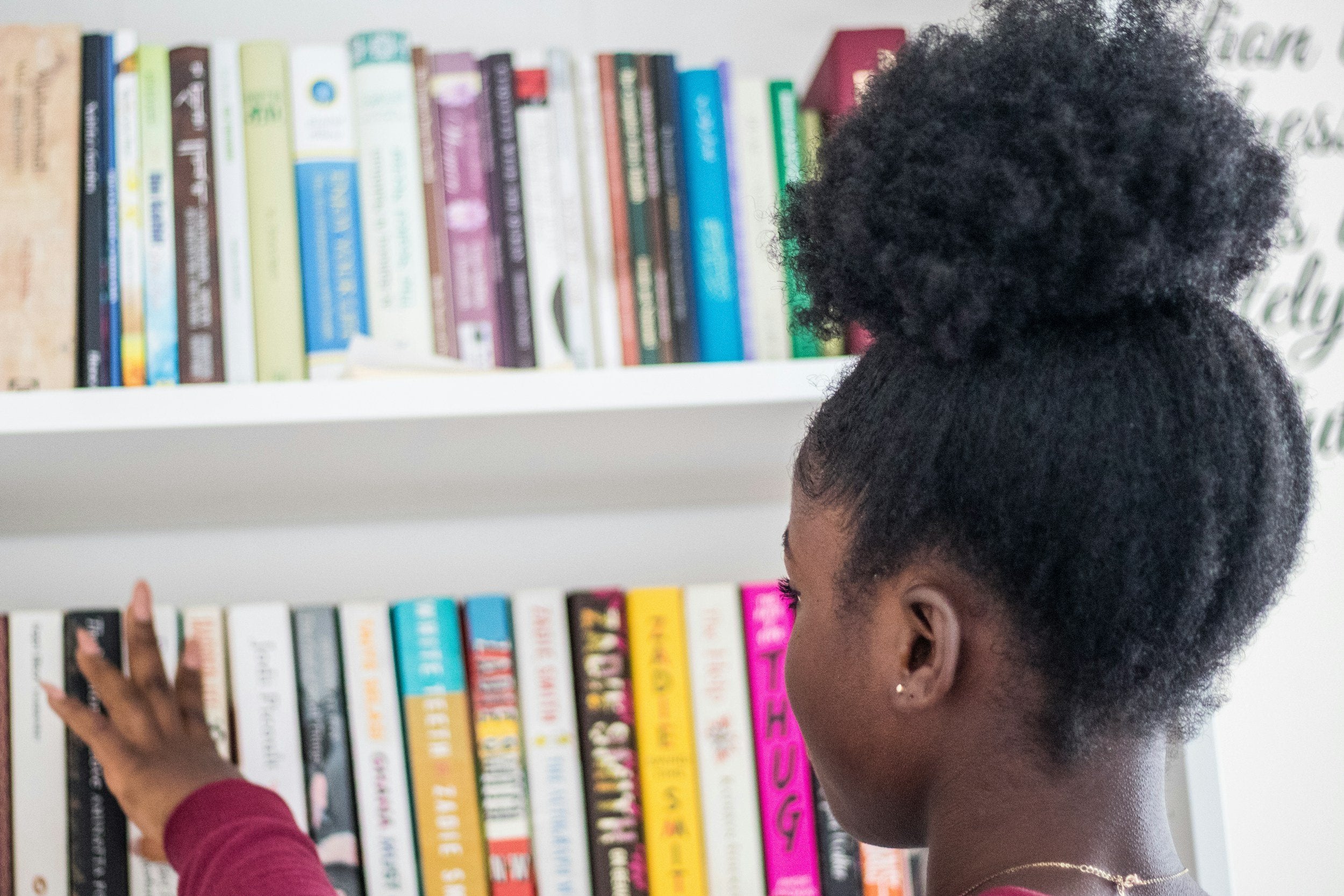 A young girl looks at a shelf of books